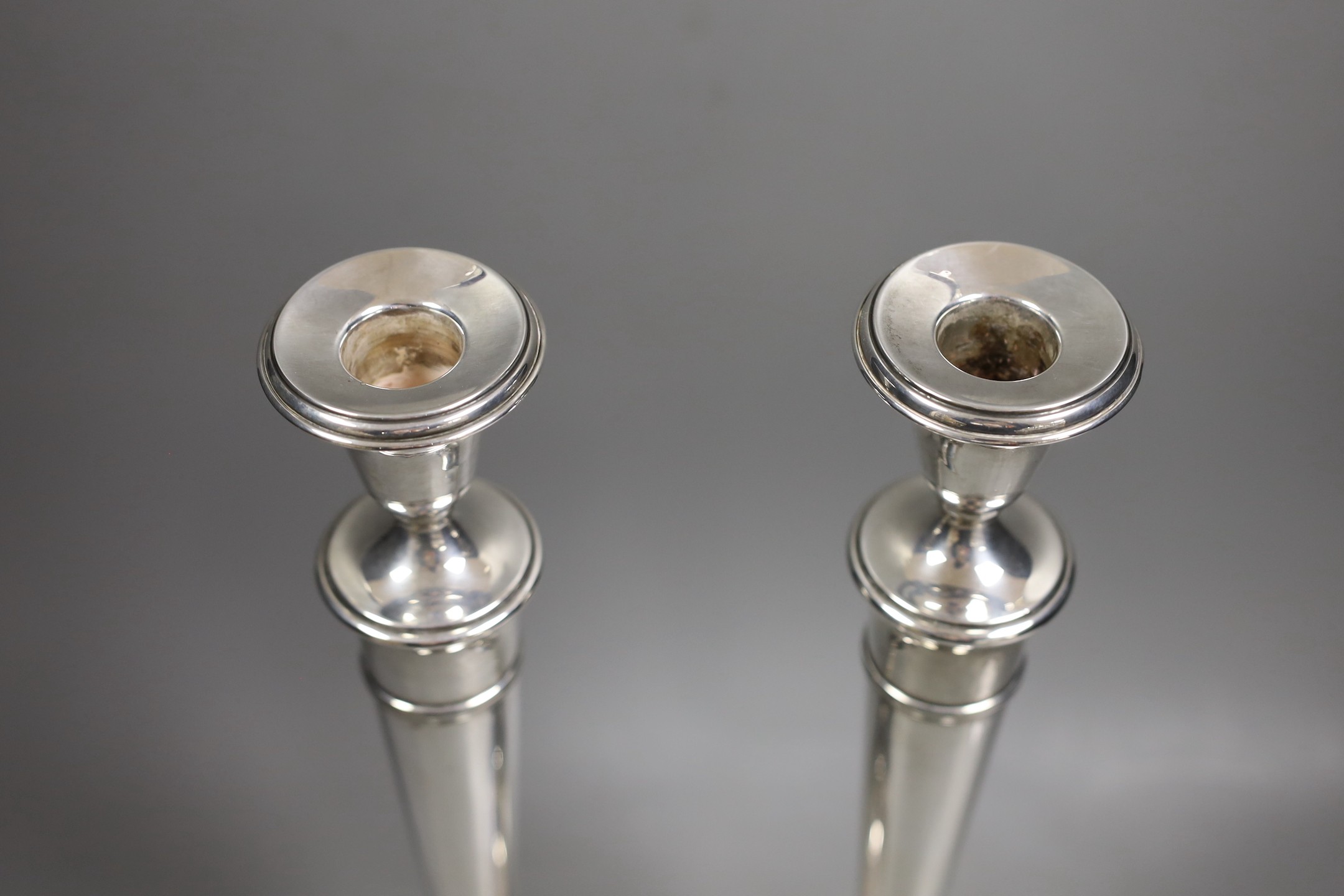 A pair of North American sterling candlesticks, with tapering stems, on circular bases, height 35.7cm, weighted.